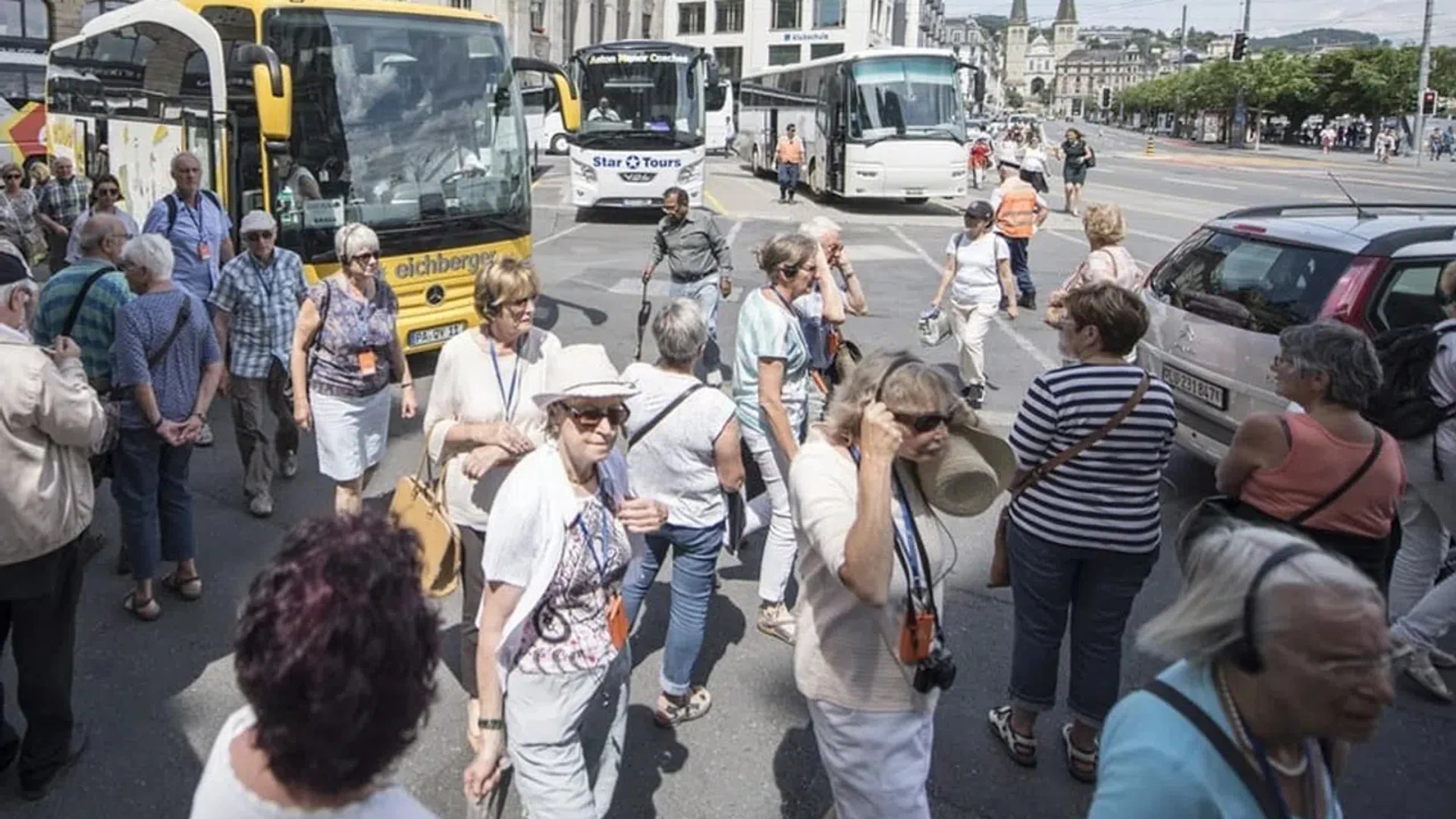 Eine Menschengruppe - Touristen - steht vor mehreren Reisebussen.