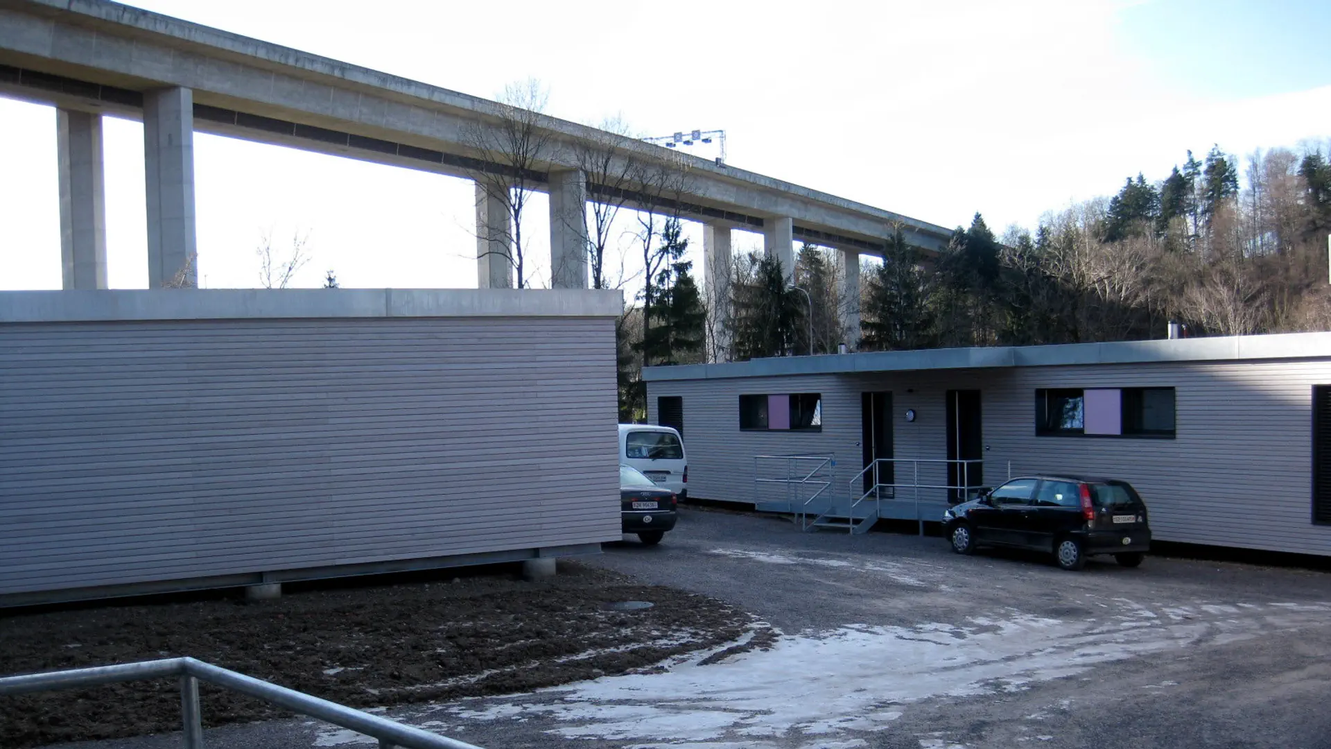 Zwei Wohncontainer stehen unter einer Autobahnbrücke