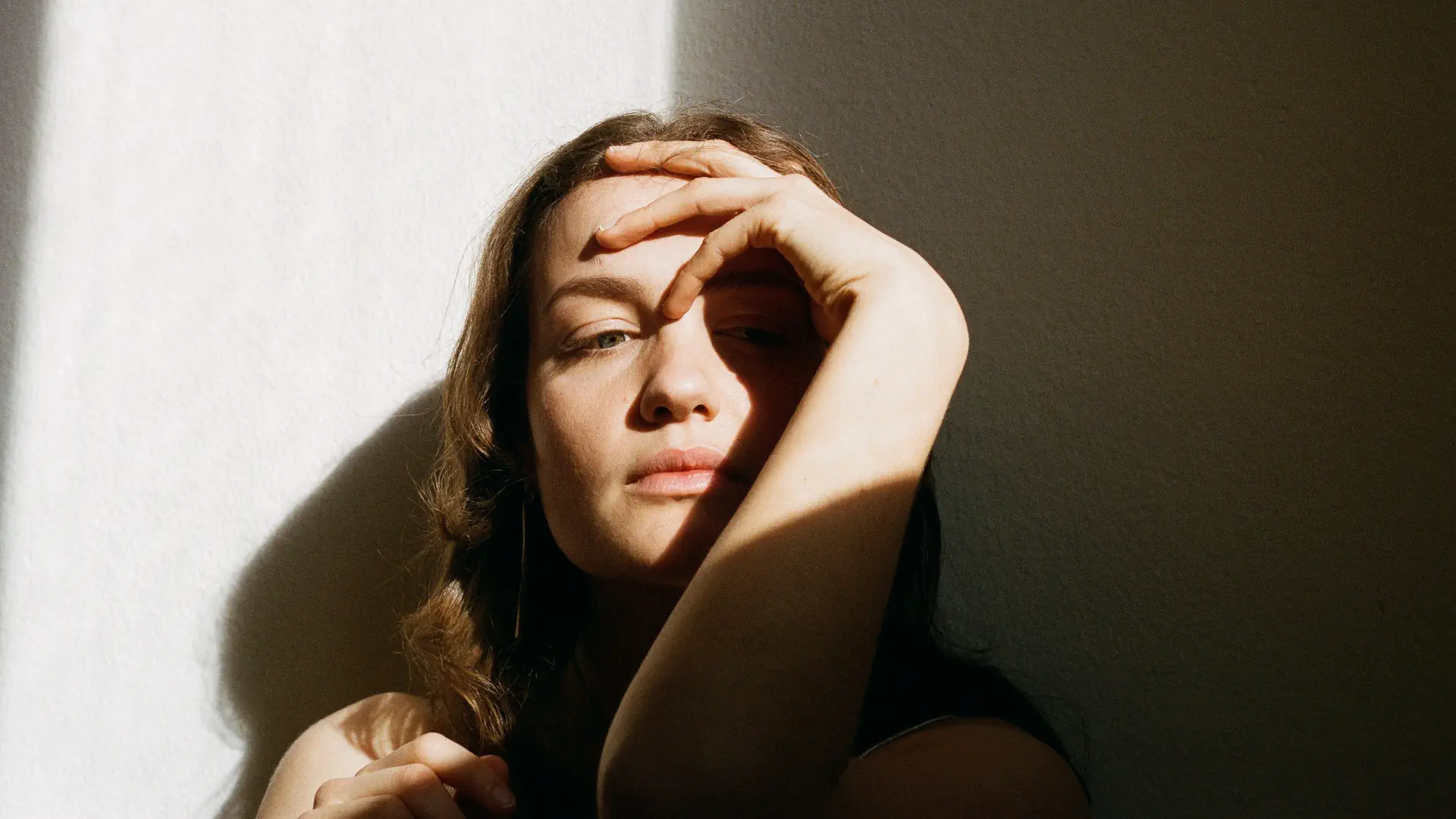 Portrait der Sängerin Melina Nora. Sie sitzt halb im Schatten und halb in der Sonne.