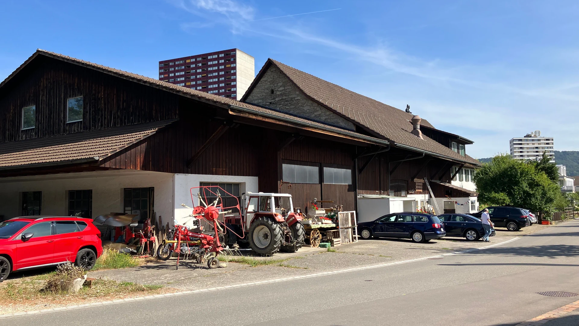 Ein Bauernhaus im alten Dorfkern von Spreitenbach. Im Hintergrund ragen Hochhäuser in den Himmel.