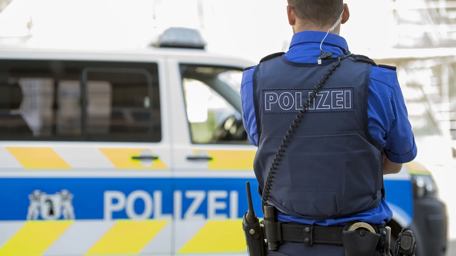 Polizist steht vor Polizeiauto