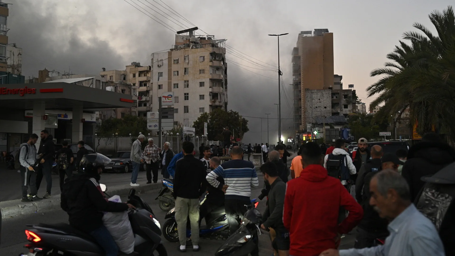 Menschen blicken auf Gebäude und Rauchschwaden in Beirut.