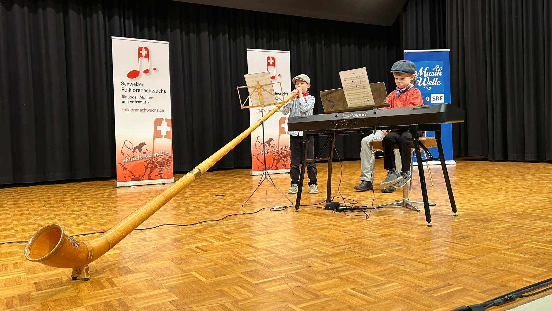 Zwei Kinder spielen Alphorn und Klavier.