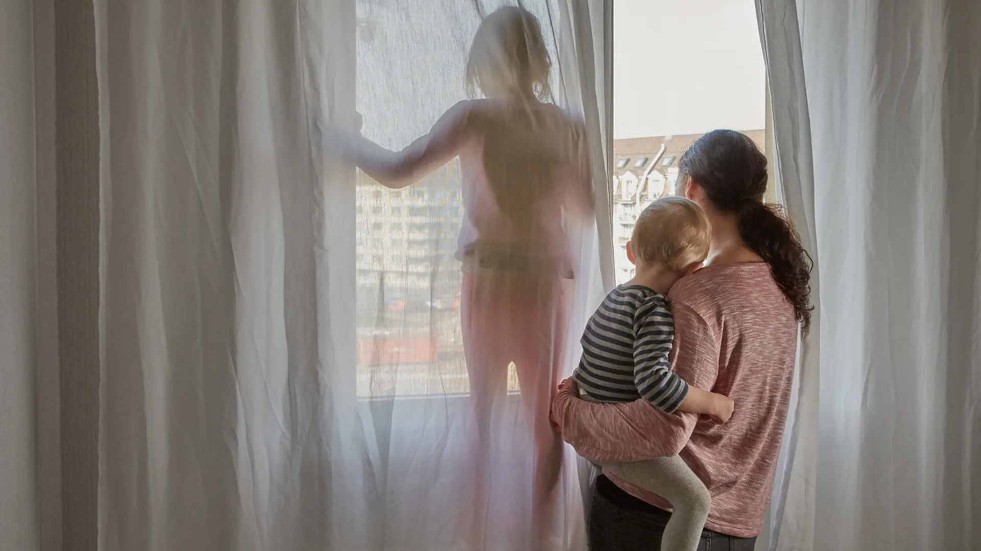 Eine Frau steht mit ihren zwei Kindern am Fenster