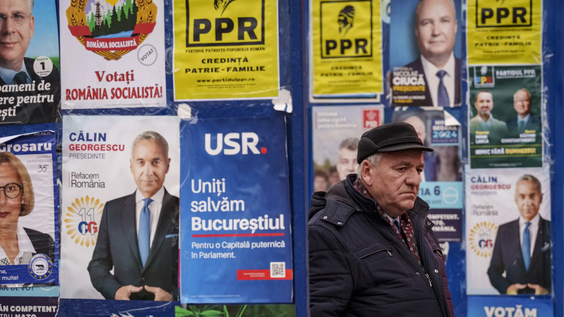 Ein Mann steht in Bukarest vor Wahlplakaten.