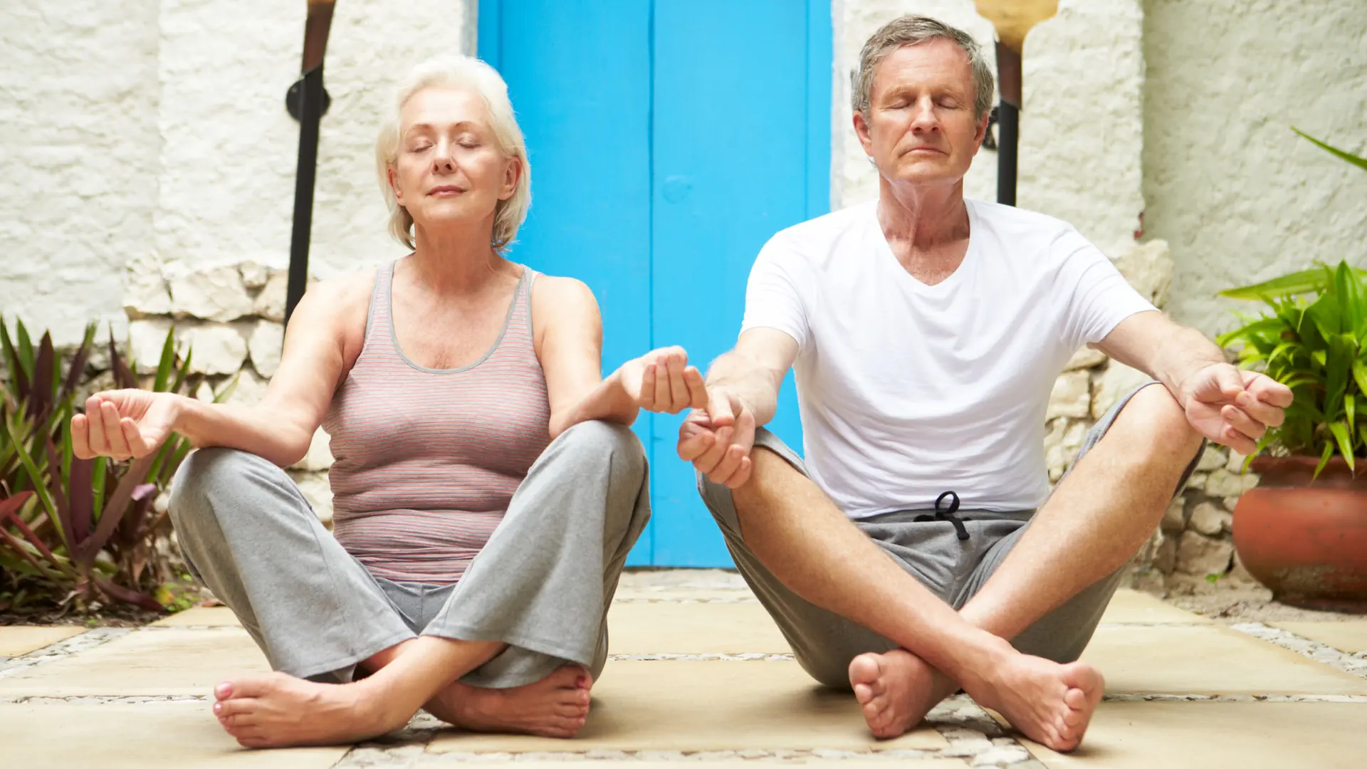 Frau und Mann machen Yoga in griechischem Hof