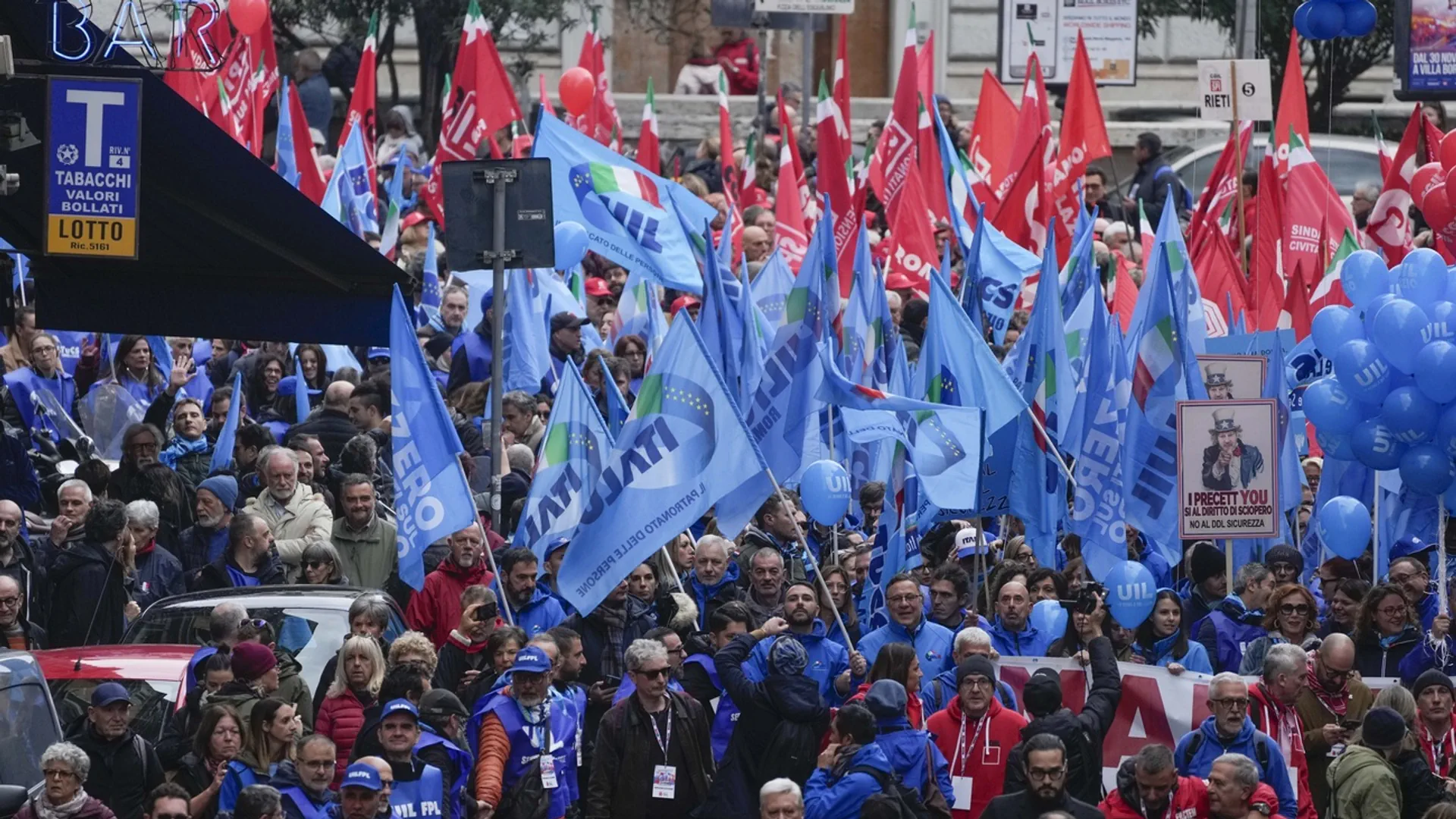 Menschen mit blauen und roten Fahnen dicht gedrängt auf der Strasse.