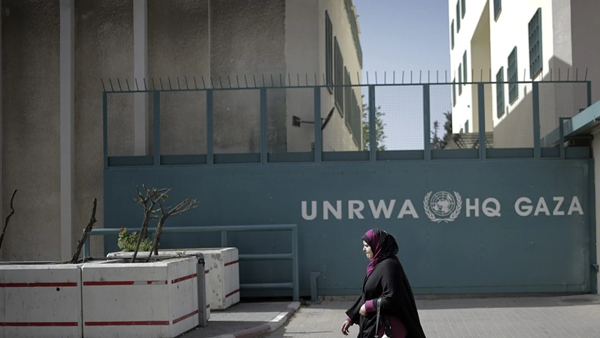 Eine Frau, welche vor einem Unrwa Schild durchspaziert.