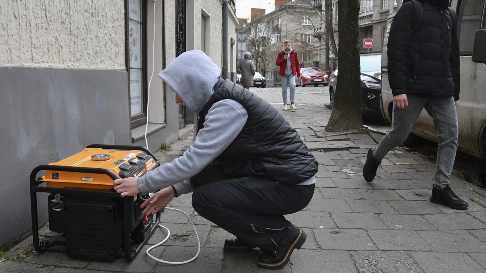 Ein Mann schraubt an einem Stromgenerator auf der Strasse.