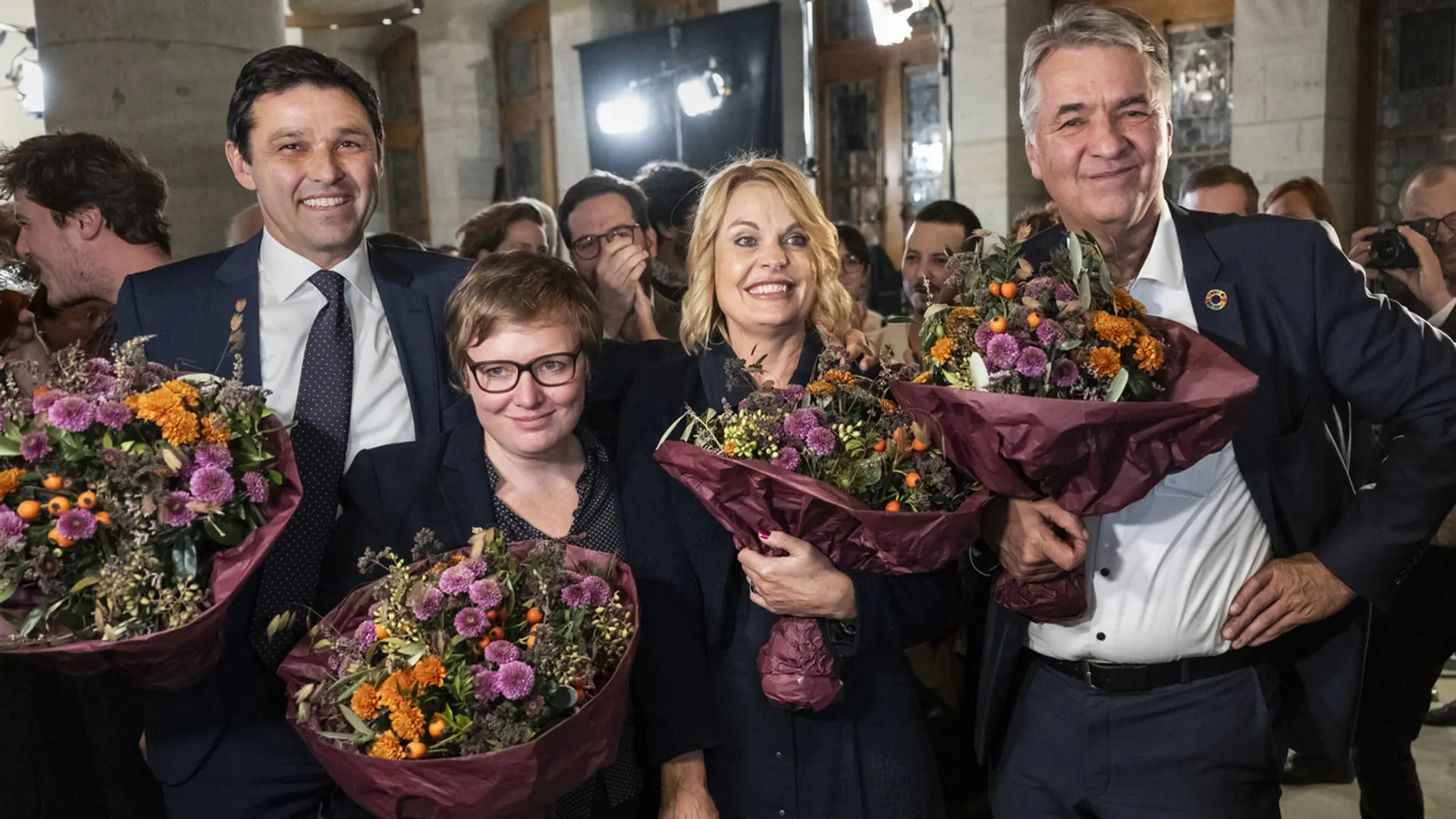 Die vier gewählten Gemeinderatsmitglieder der Stadt Bern freuen sich mit einem Blumenstrauss in der Hand über ihr Wahlresultat.