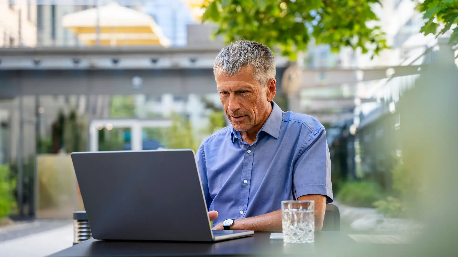 Ein älterer Mann arbeiten openair am einem Laptop.