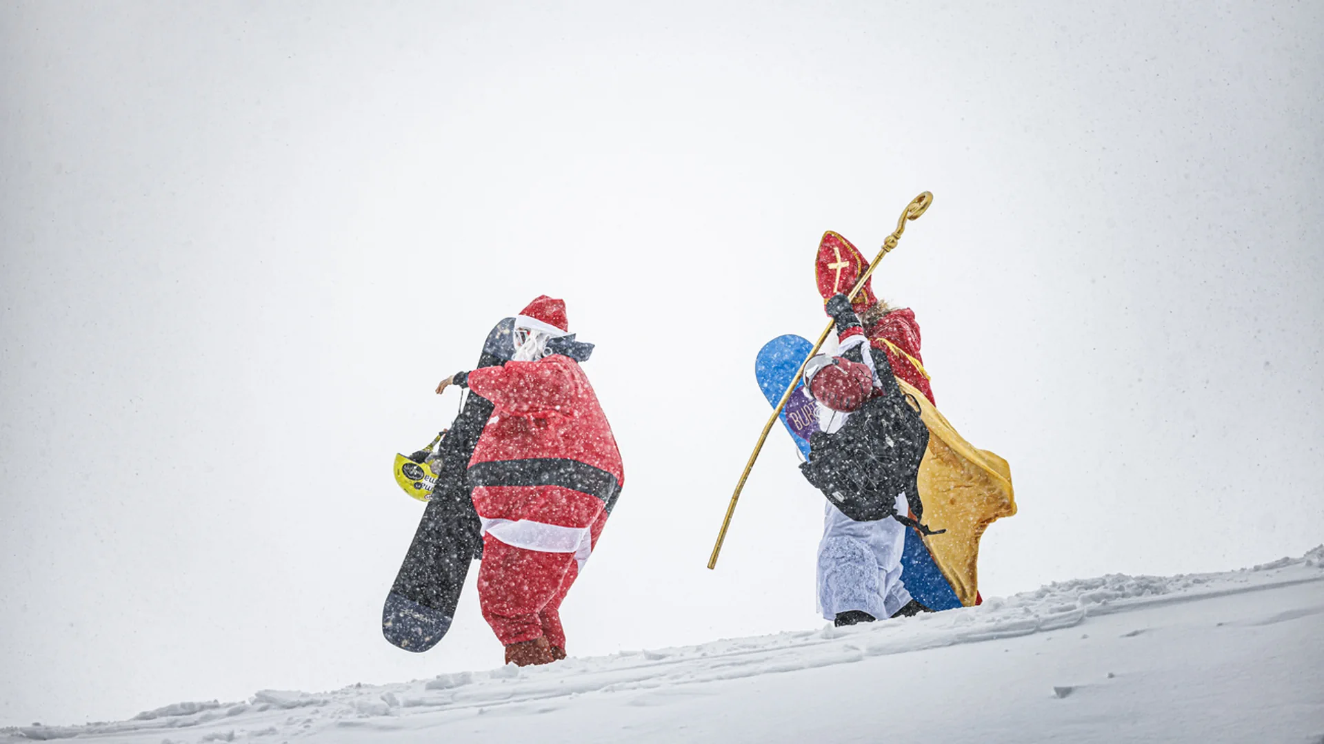 Zwei Nikolause mit Snowboards im Schnee - ob auch sie im Stress sind und sich sputen müssen?